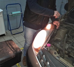 pracownik stacji diagnostycznej sprawdza ustawiania świateł w samochodzie