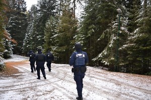 9. umundurowani policjanci idą leśną drogą