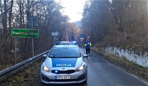 policyjny radiowóz na trasie biegu, obok jeden z uczestników w czapce mikołaja na głowie