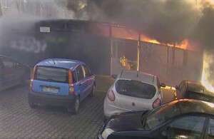 płonąca wiata śmietnikowa, obok zaparkowane samochody