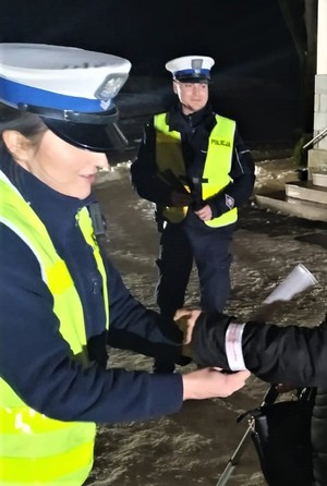 policjantka zakłada opaskę odblaskową na rękę kobiety