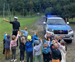 policjant i uczniowie obok radiowozu