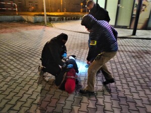 zatrzymany mężczyzna leży na chodniku, obok niego trzech nieumundurowanych policjantów