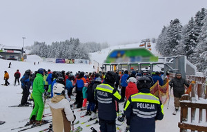 wielu narciarzy czeka w kolejce do wyciągu, obok policyjny patrol