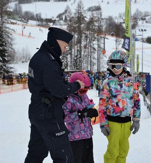 policjant wręcza małym narciarzom ulotkę z dekalogiem FIS