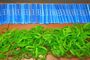 opaski położone na stole - niebieskie odblaskowe, zielone silikonowe