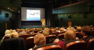 sala kinowa, słuchacze SUTW, w tle na scenie policjant wygłaszający prelekcję — kopia