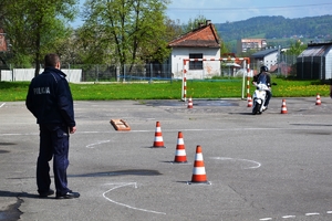 fot. arch. - uczestnik turnieju na motorowerze pokonuje tor, obok policjant