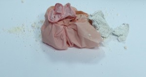 biały proszek w różowej jednorazowej rękawiczce