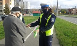 policjanta ruchu drogowego zakłada odblask na rękę seniora