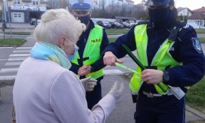 policjanta ruchu drogowego zakłada odblask na rękę starszej pani