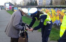 policjantka zakłada odblask na torebkę starszej kobiety