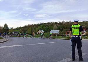 policjant ruchu drogowego nadzoruje przejazd kolarzy