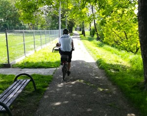 policjant jedzie na rowerze przez park