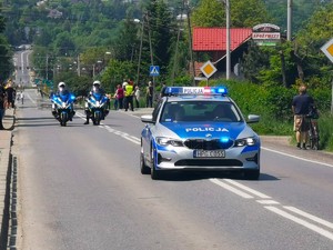 policyjny radiowóz i dwa motocykle na trasie podczas zabezpieczenia wyścigu