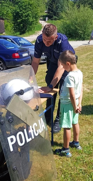 policjant z chłopcem przy stoisku ze sprzętem służbowym