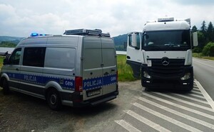 ciągnik siodłowy z naczepą, obok oznakowany radiowóz — kopia