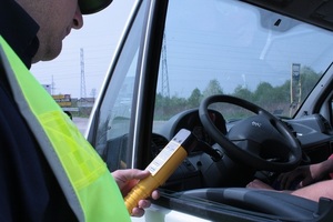 policjant z alkomatem przy kontrolowanym kierowcy siedzącym w samochodzie