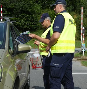 funkcjonariusze Policji i SOK wręczają materiały edukacyjne kierującemu samochodem