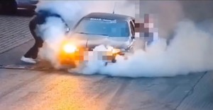 kierowca seata pali gumy, samochód przytrzymują inne osoby, wokół unosi się gęsty biały dym