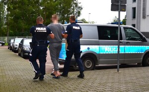 2. umundurowani policjanci prowadzą zatrzymanego do radiowozu — kopia