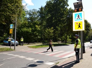 nastolatka przechodzi przez przejście dla pieszych, obok policjanci