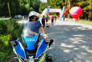 policjant ruchu drogowego na służbowym motocyklu, w tle biegacze — kopia
