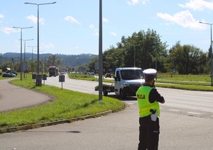 policjant WRD z laserowym miernikiem prędkości, w tle przejeżdżające pojazdy