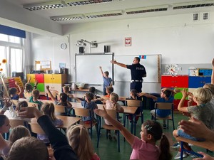 policjant uczy dzieci kierunków, wszyscy ręką wskazują lewo