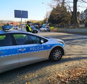 okolice cmentarza, policjant stojący przy radiowozie