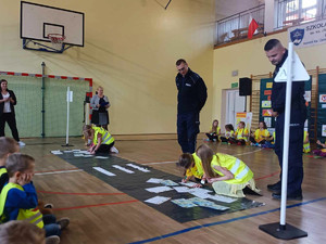 policjanci nadzorują przebieg konkursu, uczniowie rozwiązują zadania w sali gimnastycznej