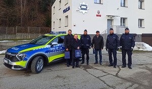 wspólne zdjęcie uczestników spotkania przy radiowozie przed budynkiem komendy — kopia