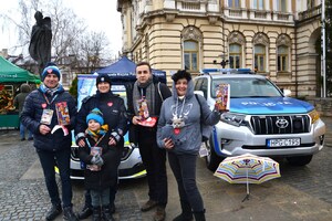 wolontariusze i funkcjonariuszka przy policyjnych radiowozach