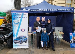 wspólne zdjęcie mężczyzny z małymi dziećmi i policjantki przy stoisku profilaktycznym