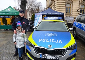 wspólne zdjęcie policjanta i dziewczynki przy radiowozie