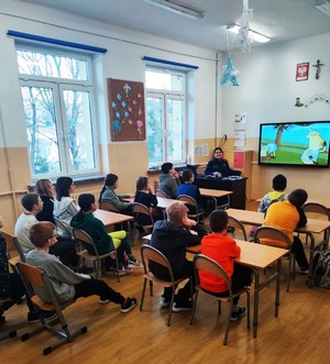 funkcjonariuszka prezentuje uczniom edukacyjny materiał multimedialny